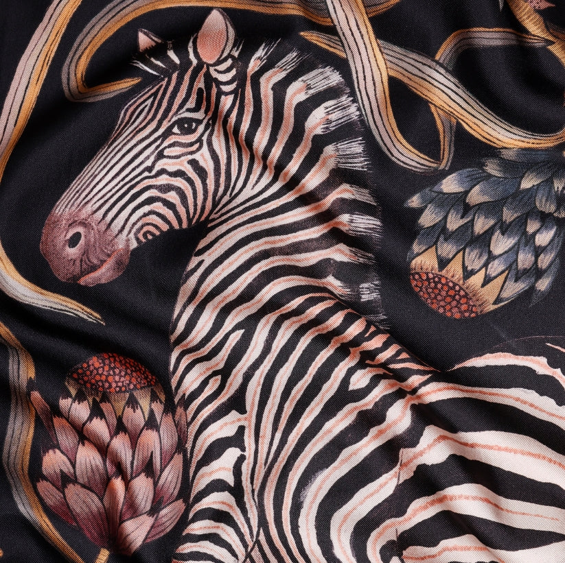 A detailed section of the scarf, highlighting a zebra surrounded by delicate protea flowers and golden botanical accents.