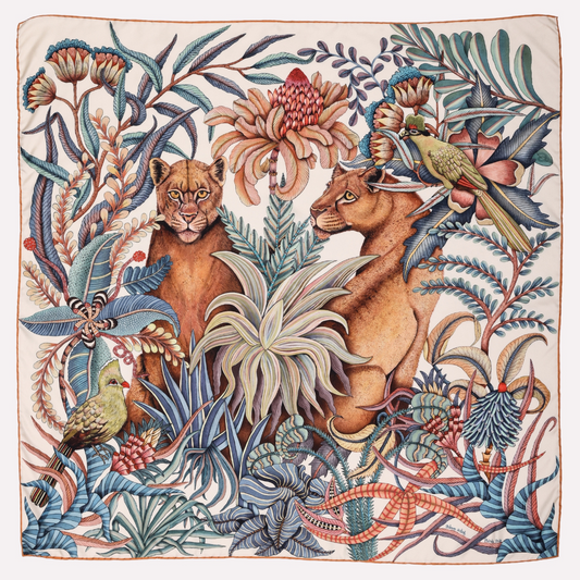 A silk scarf featuring two lionesses in a lush African forest, surrounded by intricate foliage and a detailed botanical pattern in soft misty blue and earthy tones.