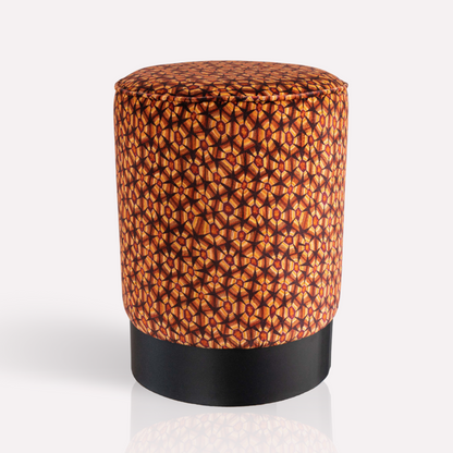 A cylindrical velvet pouffe featuring a rich plum-hued tortoise shell pattern, set against an elegant black powder-coated base.