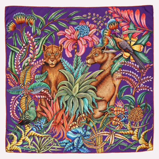 A bold, vibrant silk scarf featuring two lionesses in a lush tropical forest, surrounded by intricate botanical patterns in rich purple, pink, and blue hues.