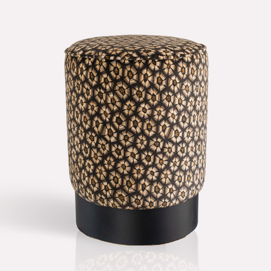 A cylindrical velvet pouffe with a refined tortoise shell-inspired pattern in silver tones, resting on an elegant brass base.