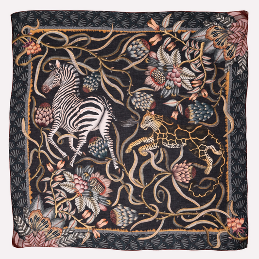  A luxurious wool and modal blend wrap featuring a detailed safari-inspired pattern with zebras, leopards, and botanical elements in a rich, dusk-toned colour palette.