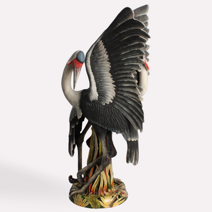 A stunning ceramic sculpture of two Wattled Cranes, one with its wings fully outstretched, poised for flight. The intricate detailing of the feathers, lifelike posture, and naturalistic base capture the elegance of these endangered African birds.