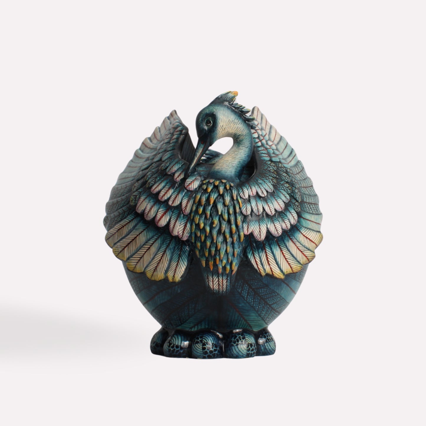 A stunning, hand-crafted ceramic vessel depicting a majestic black heron with intricately sculpted wings and a sleek, curved form. The deep blue and gold hues highlight its luxurious, artistic detailing.