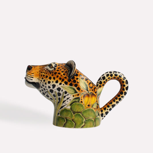  A hand-painted ceramic jug shaped like a leopard’s head, with intricate detailing and a curved handle resembling the animal’s tail.