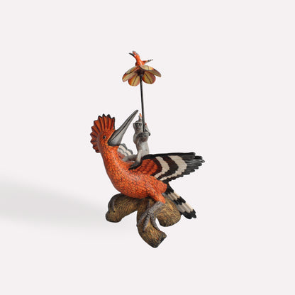 A side-angle view of the hoopoe sculpture, highlighting its black-and-white wing markings, the perched monkey rider, and the intricate hand-painted detailing on both figures.