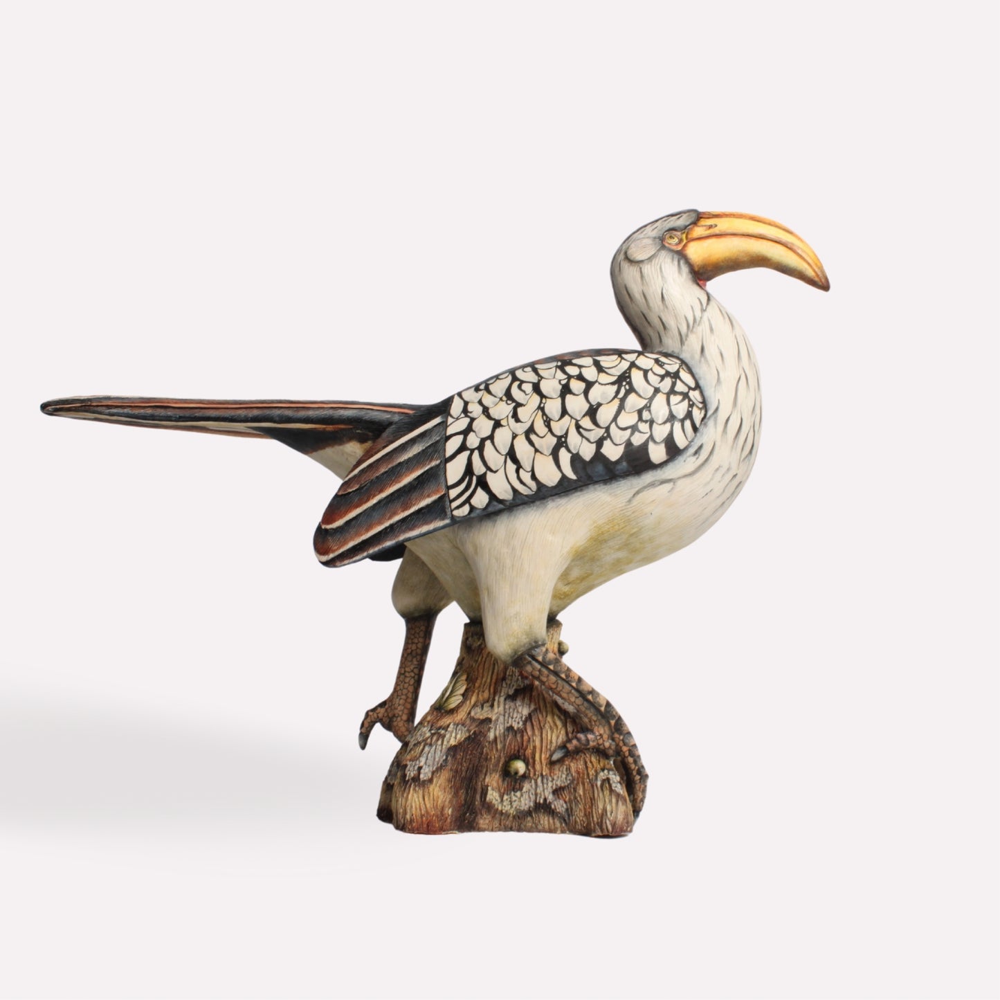 A handcrafted ceramic sculpture of a hornbill perched on a textured base. The bird’s long tail extends gracefully behind, and its beak is painted in a natural golden hue, enhancing the lifelike details.