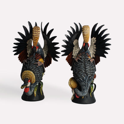 A pair of majestic crowned crane candle holders with intricately sculpted black and gold feathers. The birds' elegant, elongated crests rise into candle-holding structures, blending form with function.