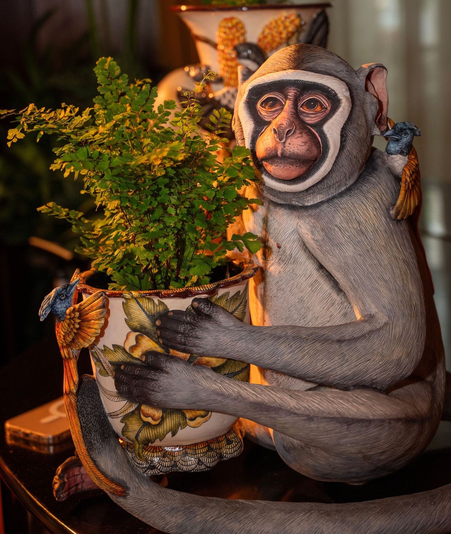 The sculpture displayed in a styled interior setting, with a lush green plant inside the planter, emphasizing its use as both an art piece and a functional planter.