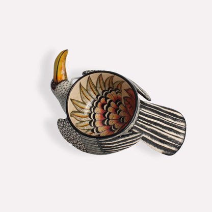 A handcrafted ceramic bowl in the shape of a hornbill, featuring a black-and-white striped body, a vibrant orange and yellow beak, and an intricate floral pattern inside the bowl.