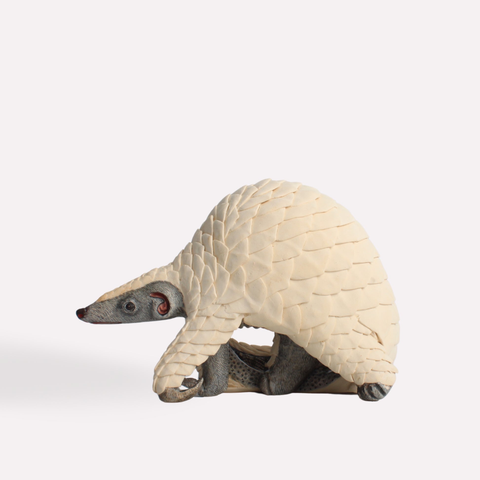 A three-quarter perspective of the sculpture, capturing the natural curvature of the pangolin’s body and the lifelike detailing of its protective scales.