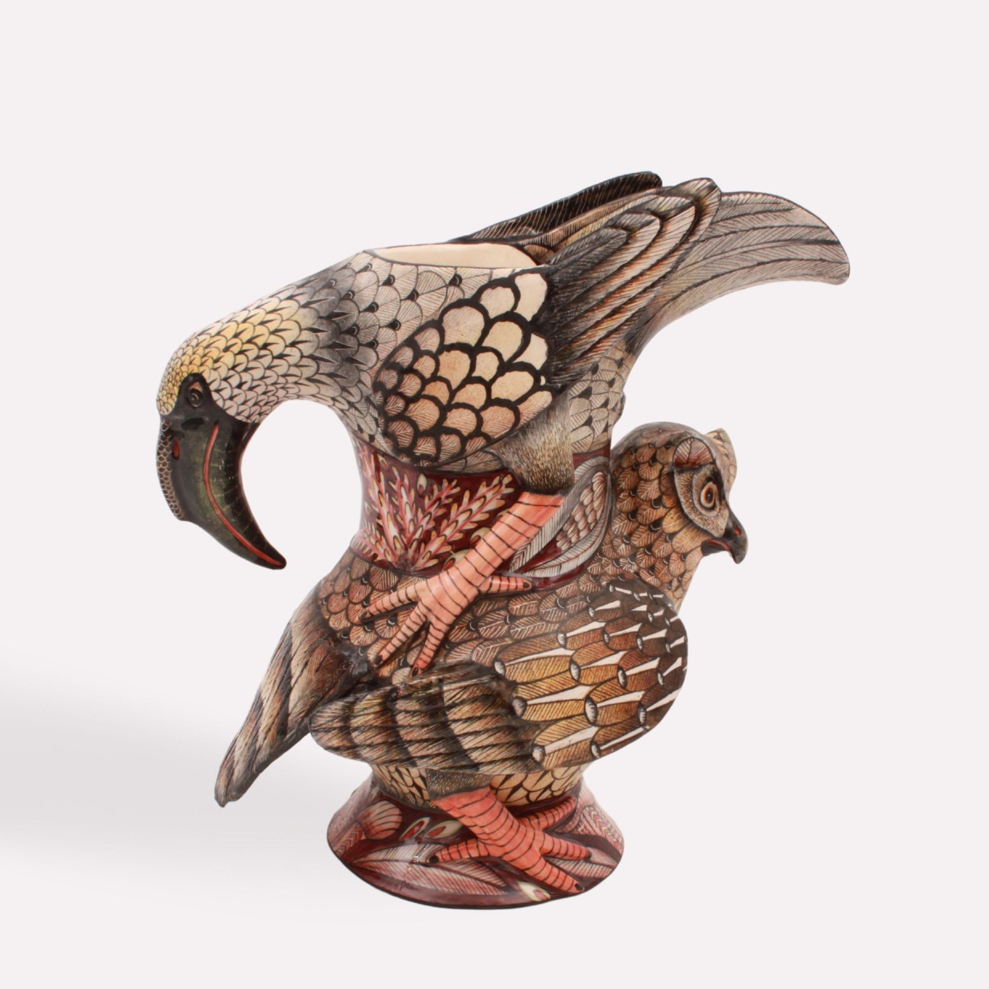 A handcrafted ceramic jug featuring a detailed hornbill perched on top of an owl. The jug has an earthy-toned feather pattern, with the hornbill's curved beak extending forward as part of the jug's spout.