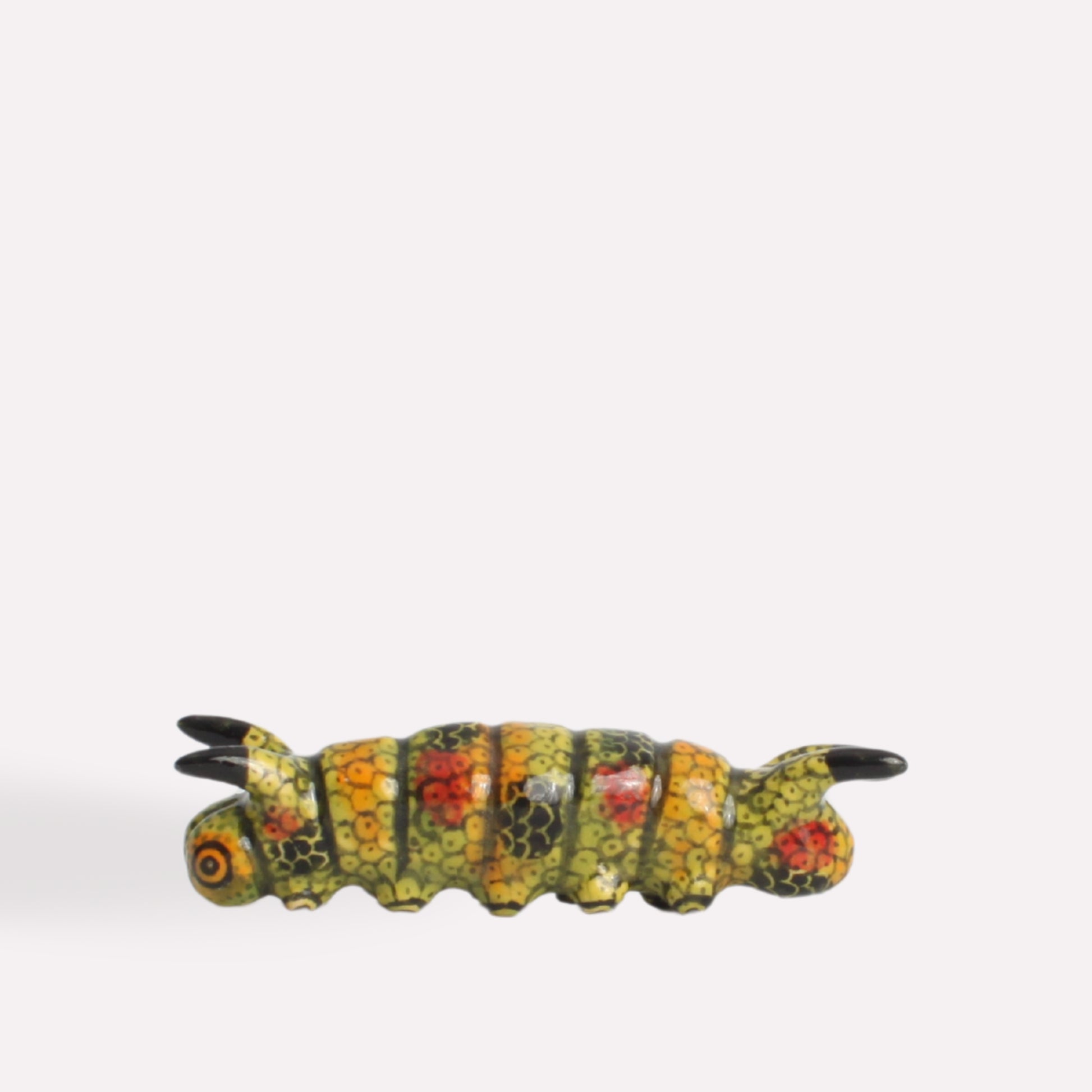 A side-angle view of the ceramic caterpillar, showcasing its curved body, intricate detailing, and lifelike texture.