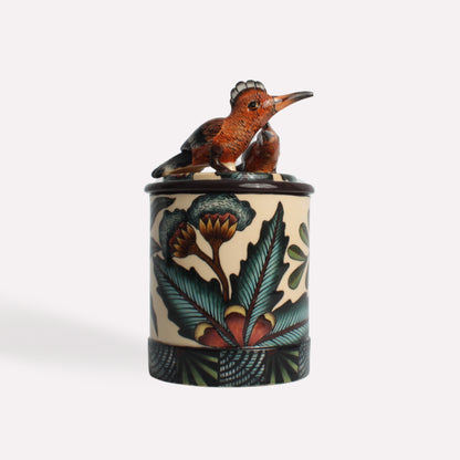 A decorative ceramic candle container showcasing intricate floral patterns and a detailed hoopoe bird sculpture on the lid.