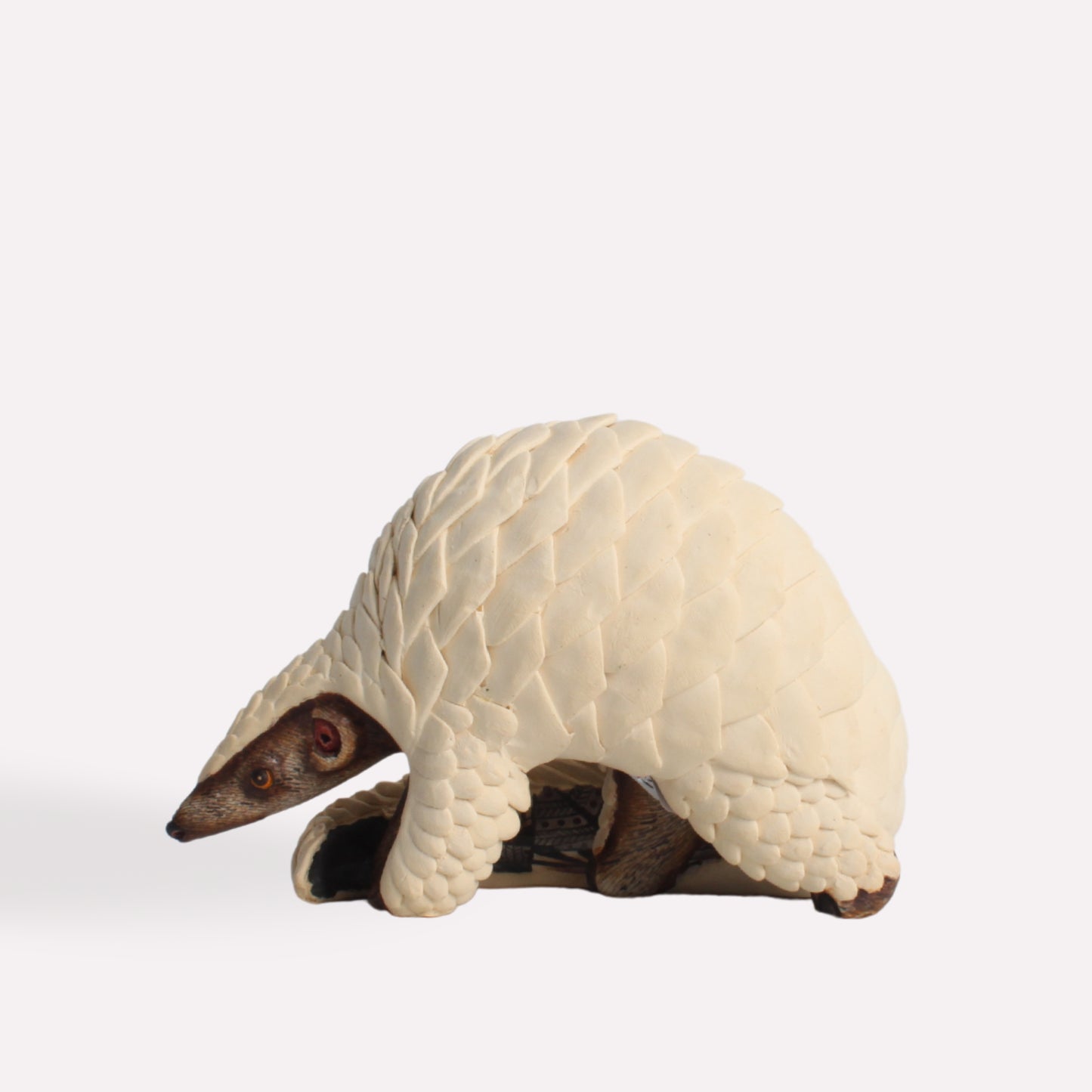 A profile shot of the pangolin sculpture, emphasizing the rounded shape of its protective scales and its curled resting position.