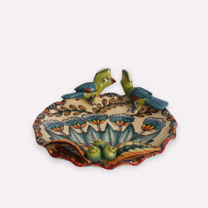 A side perspective of the decorative coin dish, showcasing its slightly curved edges and intricate detailing of the bird and floral motif.