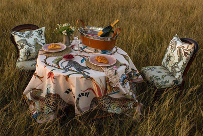 A beautifully set outdoor dining table covered with the Monkey Paradise Square Tablecloth, featuring champagne flutes, fine tableware, and a lush natural backdrop, creating a luxurious safari-inspired dining experience.