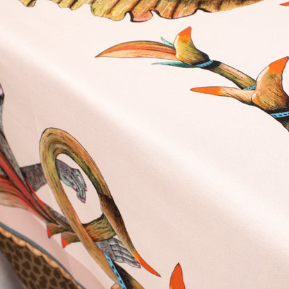 A perspective shot of the tablecloth hanging over the corner of a table, emphasising the contrast between its detailed border and the main design.